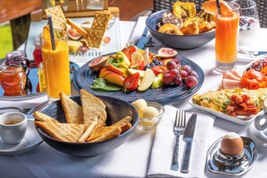 Ein Frühstückstisch mit Toast, Obst, Eiern und einem Glas Orangensaft.