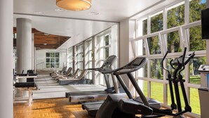Un gimnasio con cintas de correr, elípticas y piso de madera.