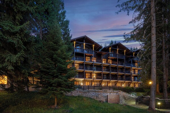 Ein mehrstöckiges Lodgehaus mit Balkonen, umgeben von Bäumen.