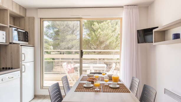 Una cuina moderna amb zona de menjador, vistes a l'exterior i preparació per esmorzar.