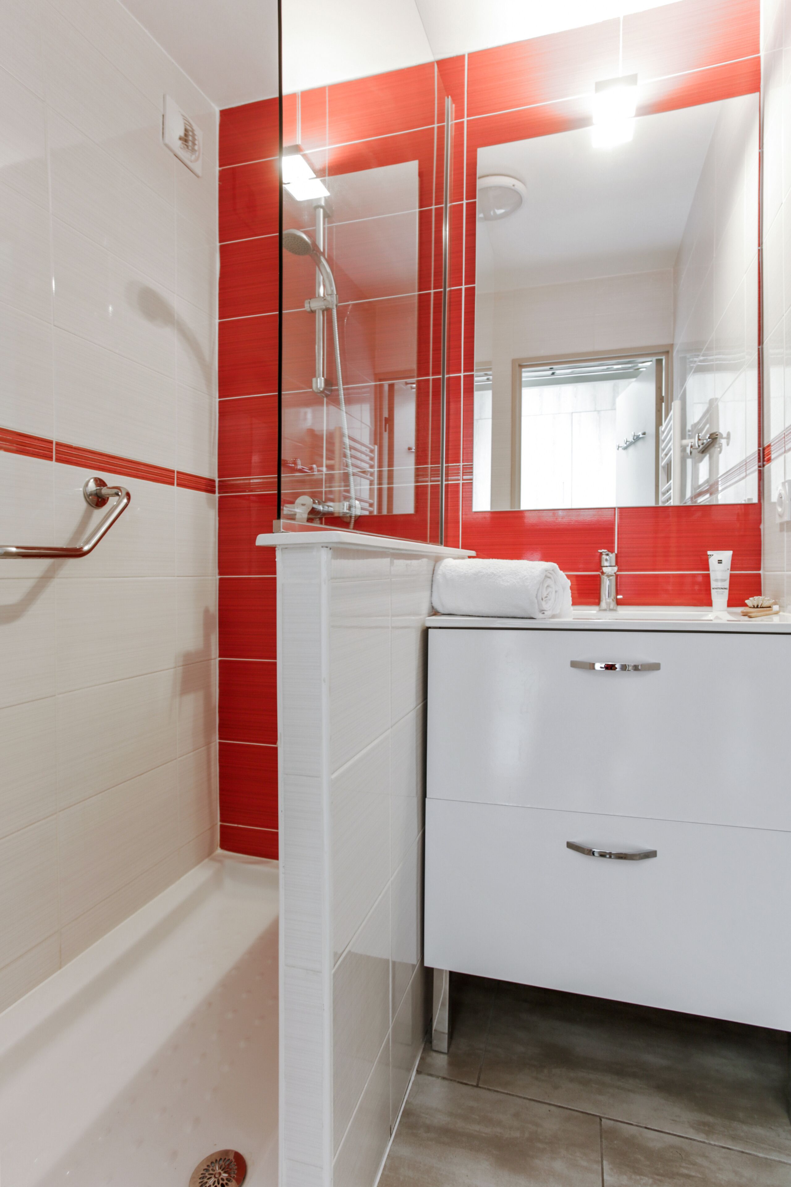 Un bagno moderno con doccia, mobile lavabo con specchio e servizi igienici.