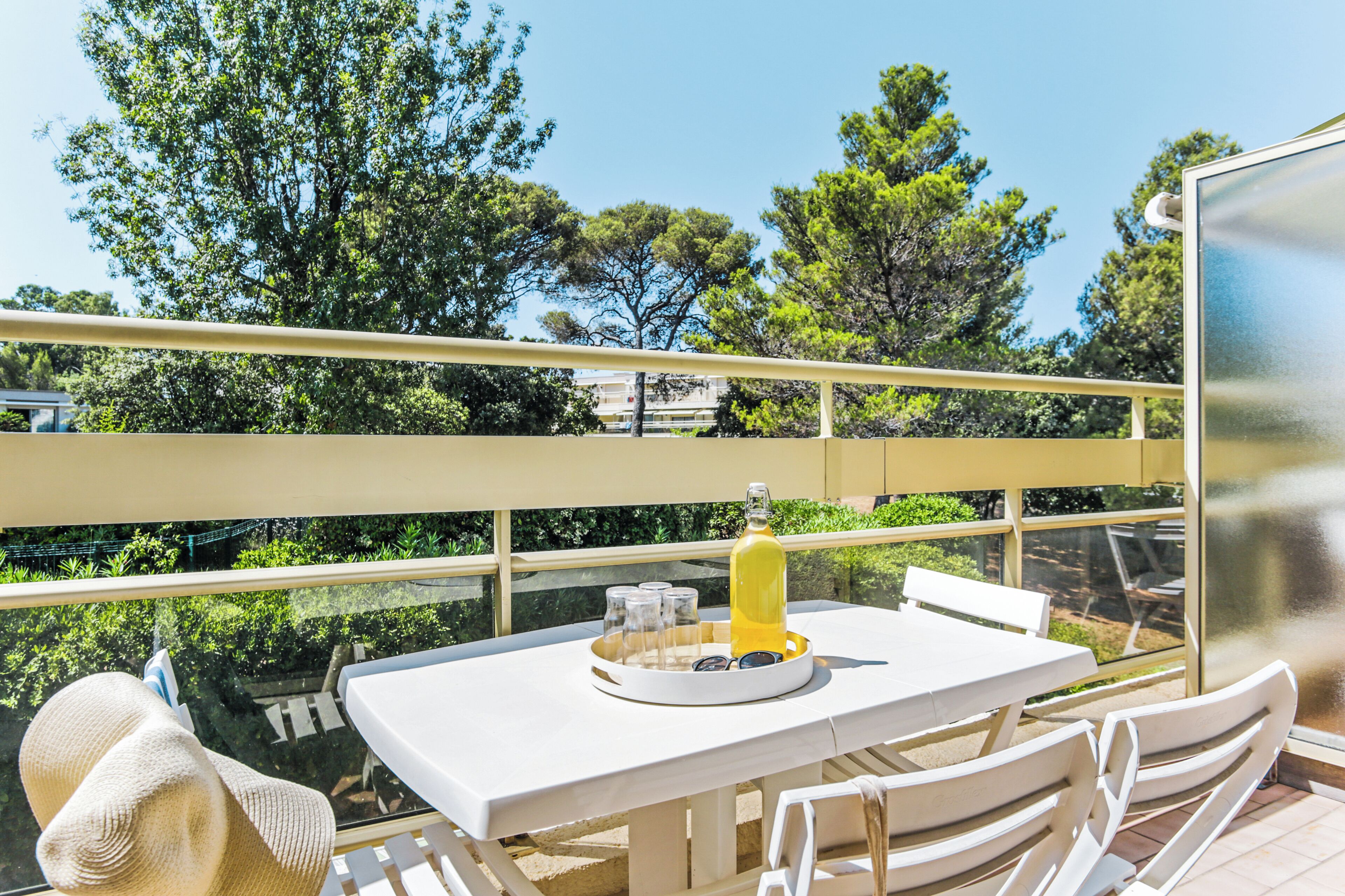 A balcony with a table, chairs, and a bottle of drink.