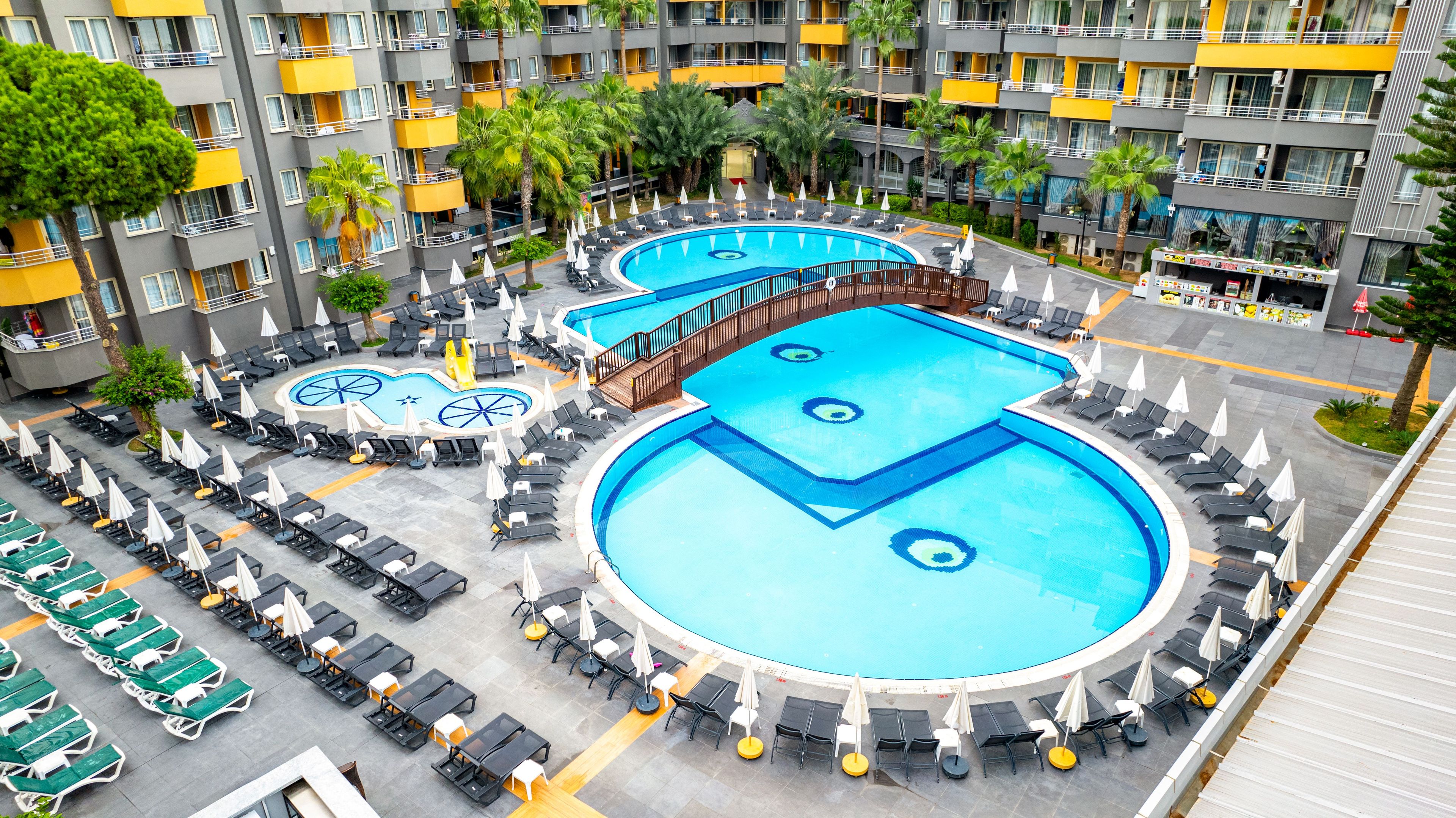 Un hôtel doté de plusieurs piscines, de chaises longues et de parasols.
