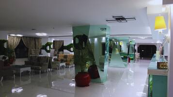 A modern lobby with a glass partition, seating area, and a reception desk.