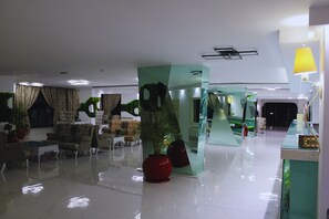 Un hall d’entrée moderne avec une cloison en verre, un espace salon et un comptoir d’accueil.