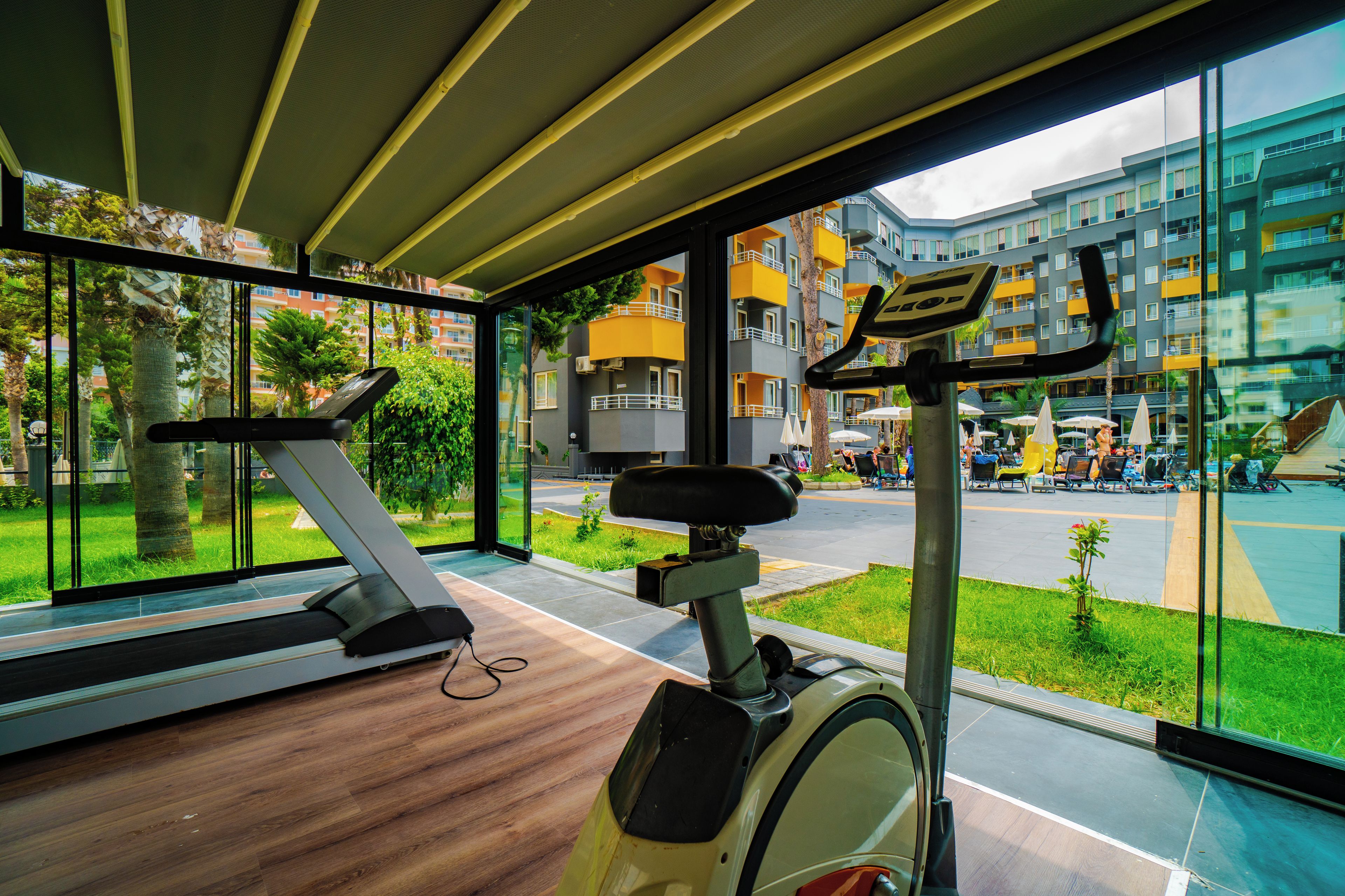 A gym with exercise equipment and large windows overlooking a cityscape.