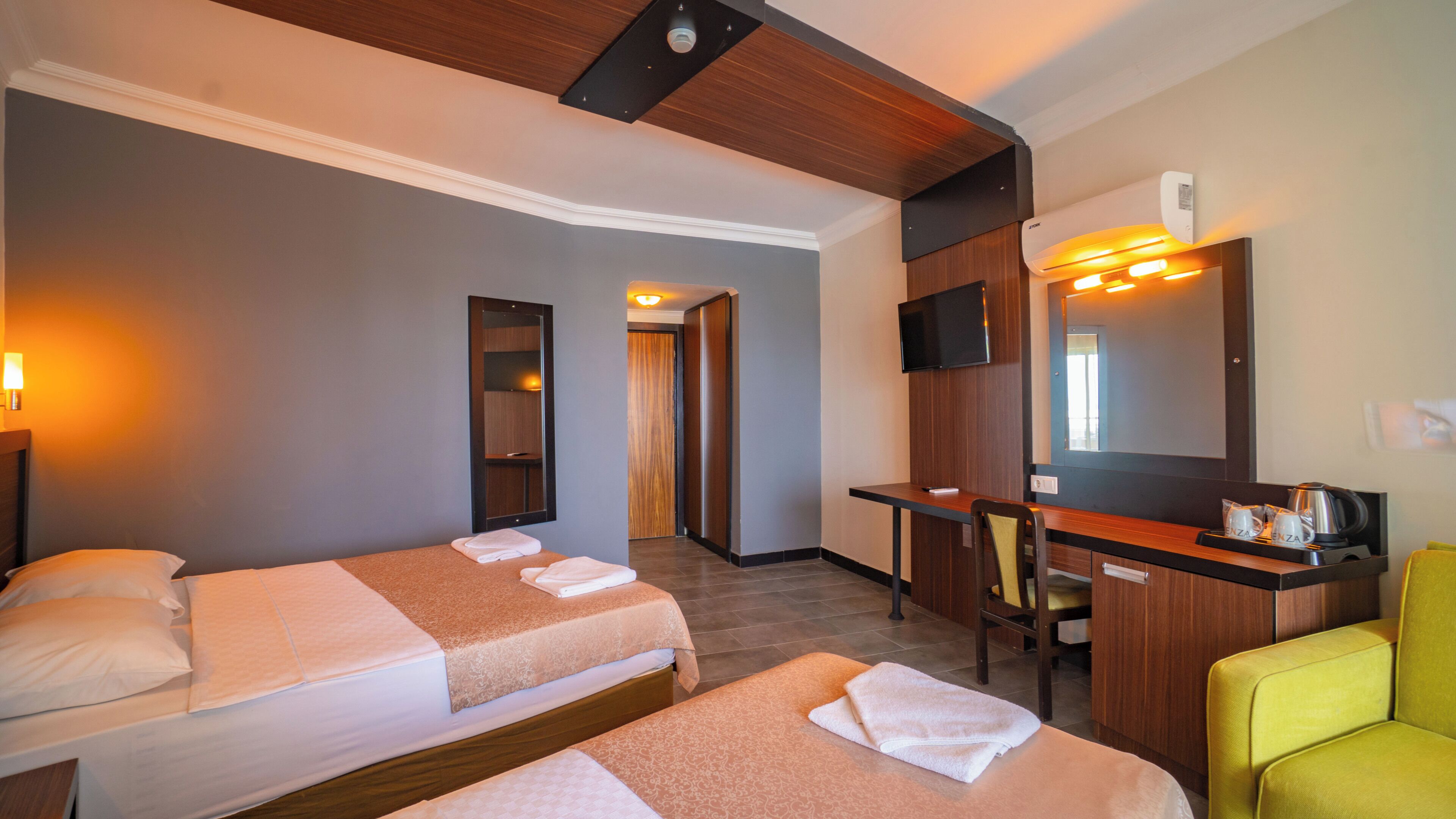 Een hotelkamer met twee bedden, een bureau, een stoel, een televisie en een spiegel.