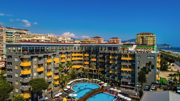 Un hôtel à plusieurs étages, doté de balcons, d’une piscine et offrant une vue sur la mer.