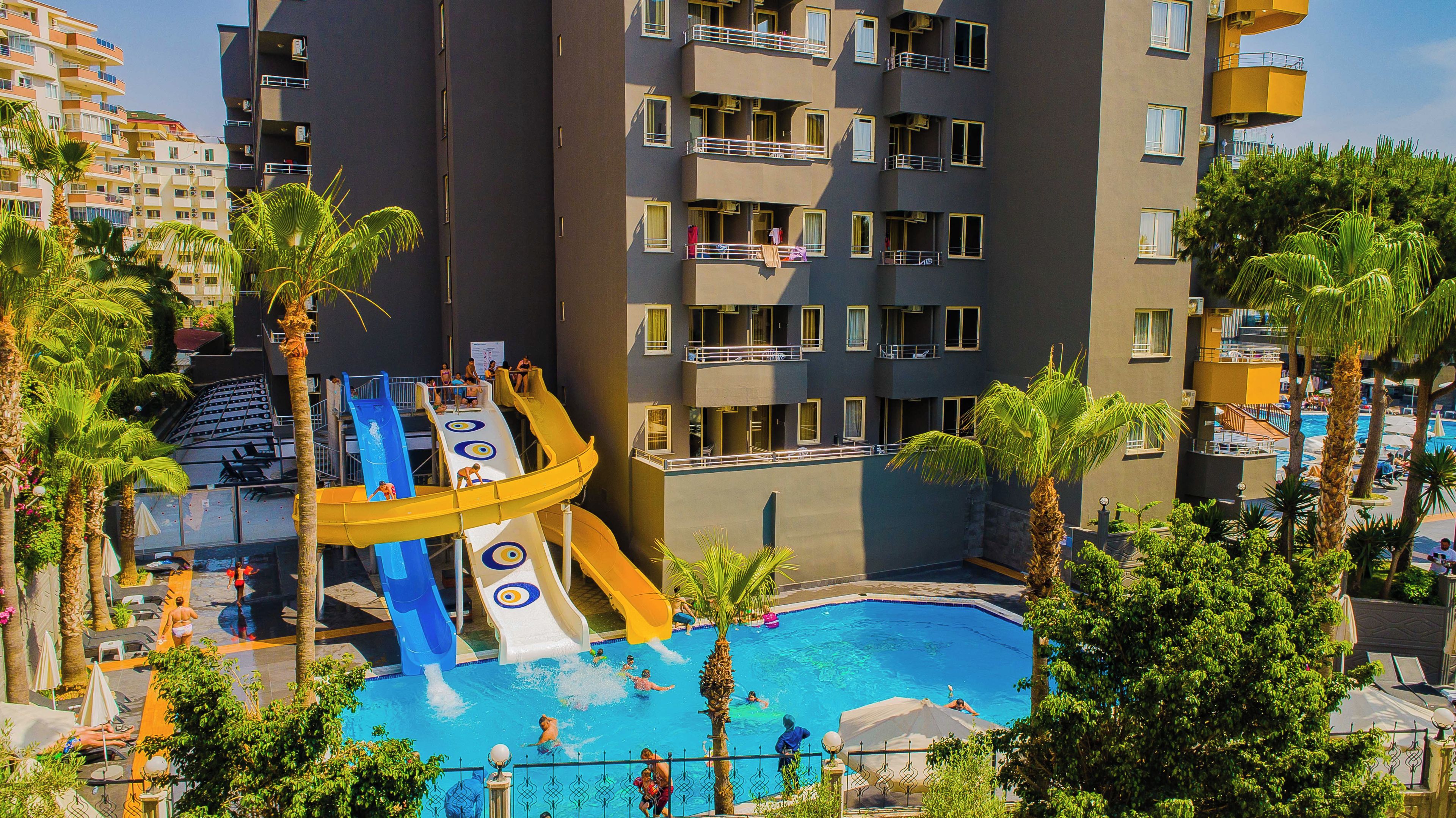 A multi-story building with balconies, a pool, and a water slide.