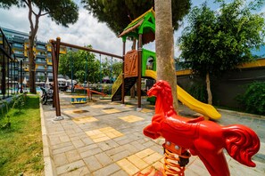 Ein Spielplatz mit Rutsche, Schaukeln und einer Kletterkonstruktion.