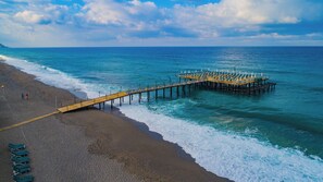 A beach with a wooden pier extending into the sea, featuring rows of sun loungers. - Senza Grand Santana Hotel (Alanya)