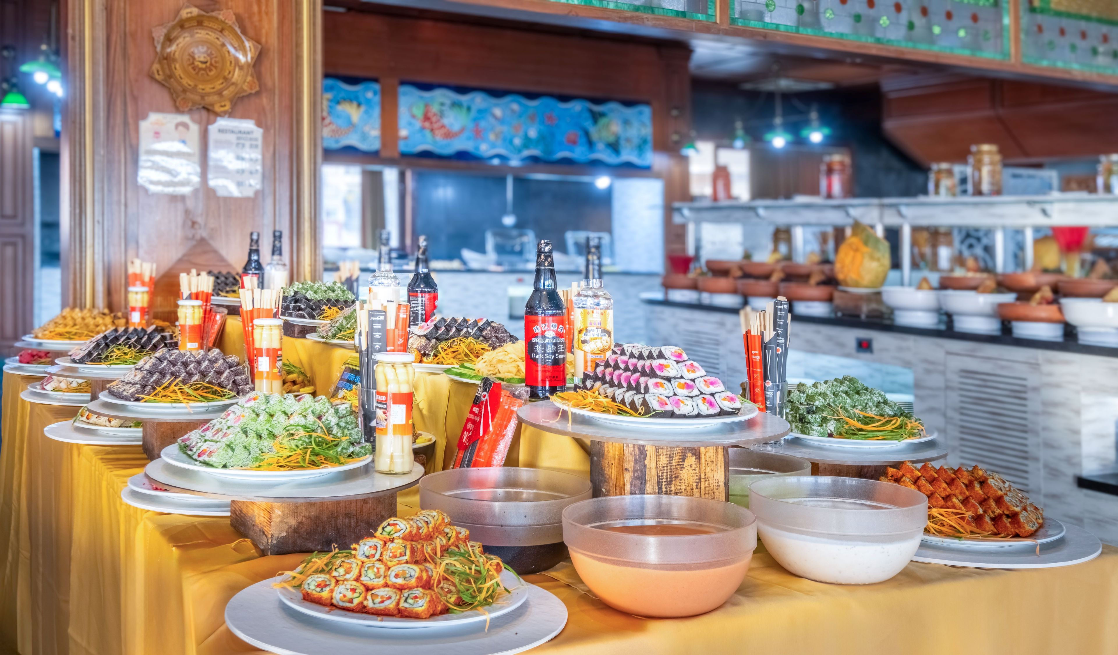 A buffet with various dishes and condiments, including sushi, salads, and sauces.