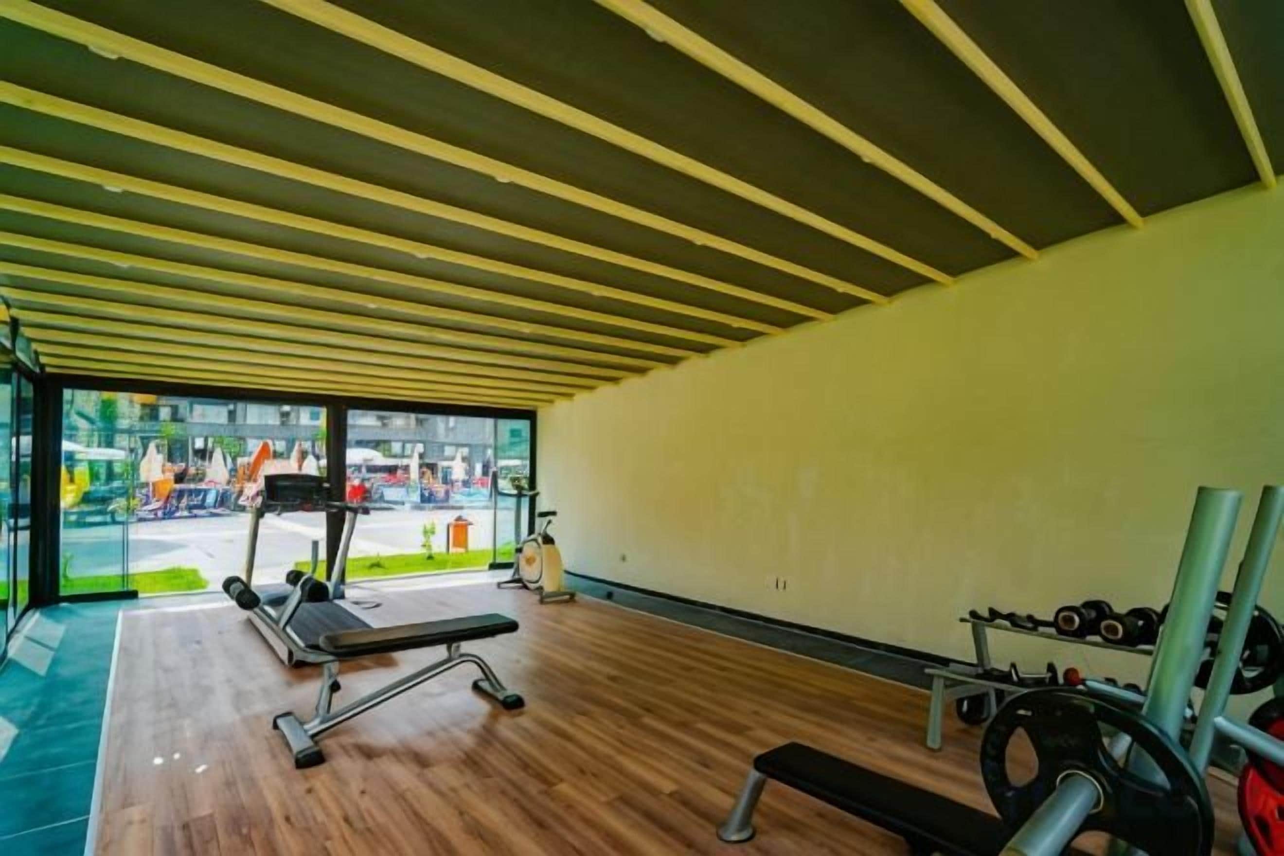 Un gimnasio con equipo de ejercicio, una banca y vistas al exterior.