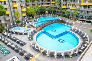 Ein Hotel mit mehreren Schwimmbecken, Liegestühlen und einem Innenhof.