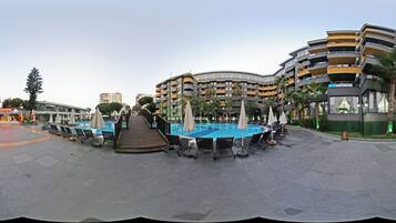 Ett modernt hotell med poolområde, utomhusplats och utsikt över de omgivande byggnaderna.