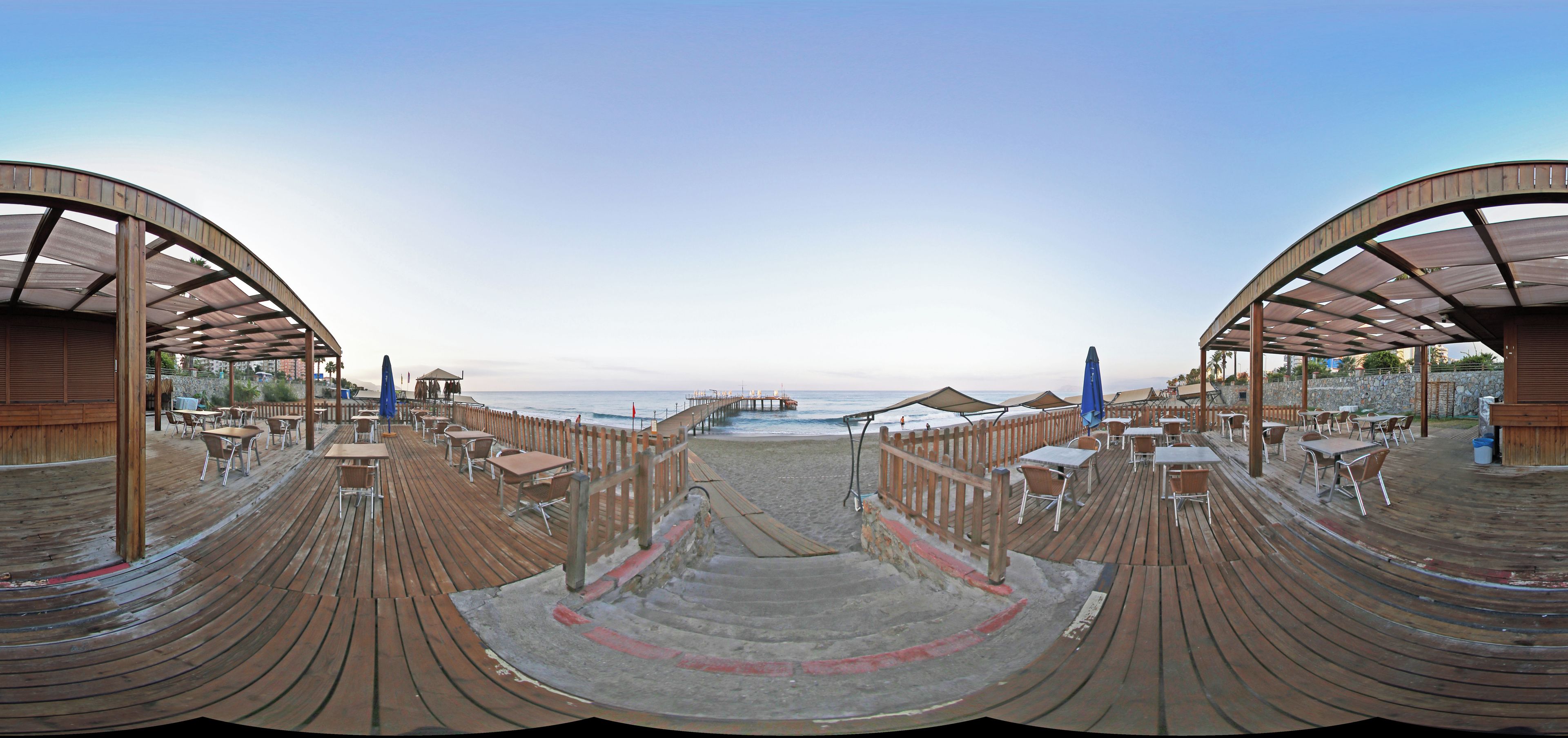 A beachside restaurant with outdoor seating and a view of the ocean.