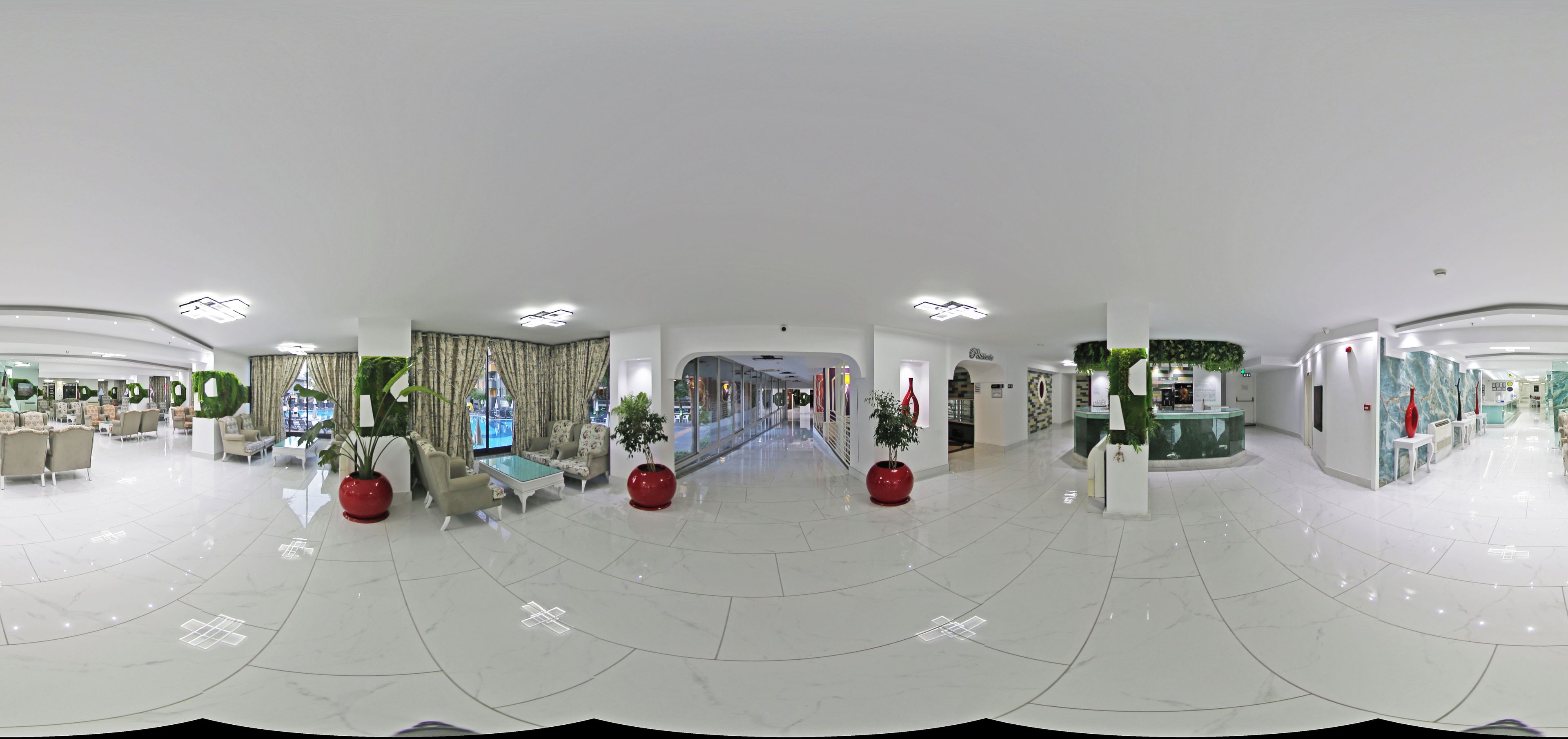 Un'ampia hall dall'arredamento moderno, con un'area salotto centrale dotata di divani e poltrone, una grande scalinata e una reception.