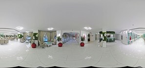Een ruime lobby met een modern ontwerp, met een centraal zitgedeelte met banken en fauteuils, een grote trap en een receptiebalie.
