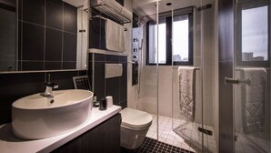 Un baño moderno con un lavamanos grande de color blanco, un inodoro, ducha con cerramiento de vidrio y un perchero para toallas.