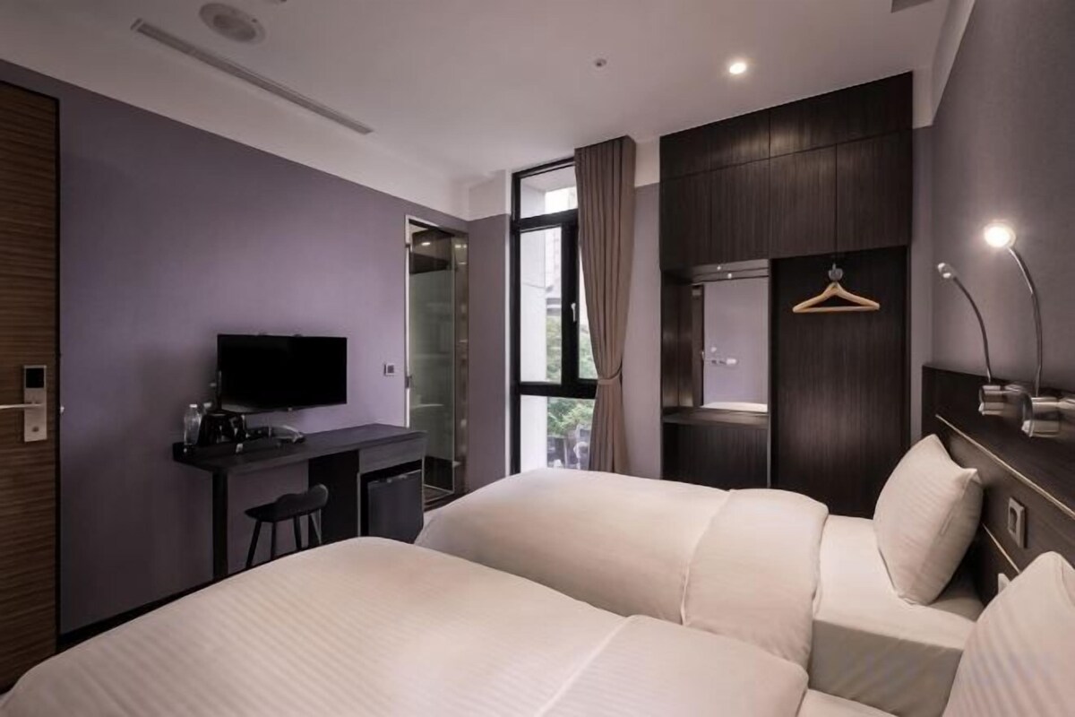 A hotel room with a bed, a desk, a television, and a mirror.
