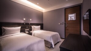 Una habitación de hotel con dos camas, un escritorio y una puerta de madera.