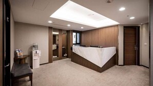 Una habitación de hotel con tragaluz, un mostrador de recepción, un dispensador de agua y un banco.
