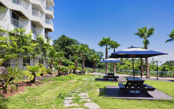 A courtyard with outdoor seating, palm trees, and a building with balconies.