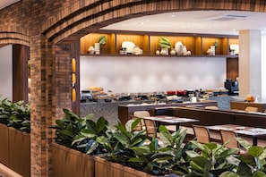 A modern restaurant with brick arches, wooden paneling, and a variety of seating options including tables and booths. - Kensington Resort Jeju Jungmun (Seogwipo)