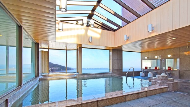 A modern indoor swimming pool with clear views of the sea, large windows, and a stone-tiled floor. - Sunmi Club (Atami)