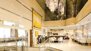 A spacious lobby with a grand staircase, a reception desk, and a chandelier. - Sunmi Club (Atami)