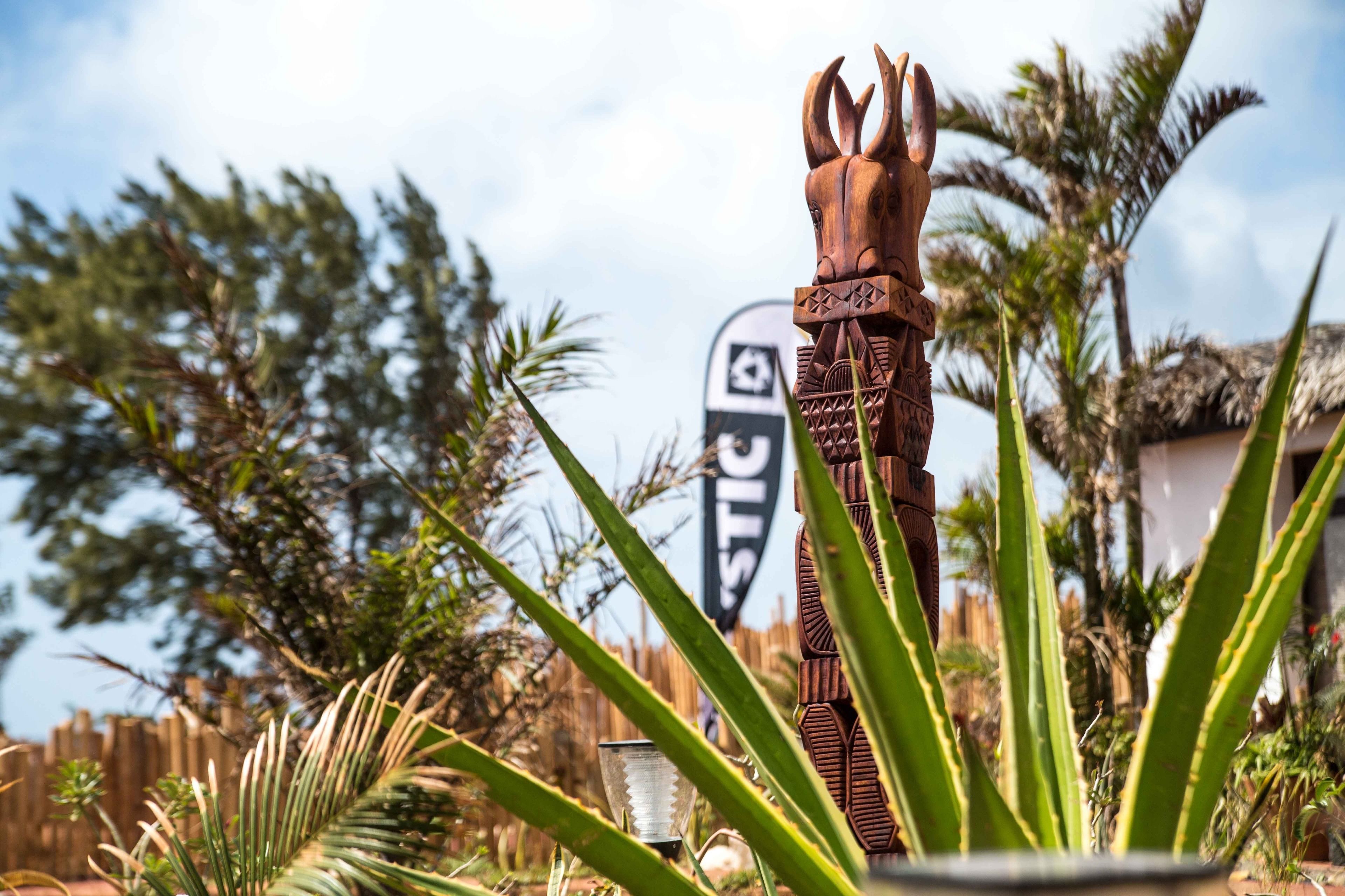 A wooden decorative structure with a horse head design, surrounded by tropical plants and a clear sky.