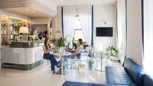 A modern hotel lobby with a bar area, seating arrangements, and a large window with curtains.