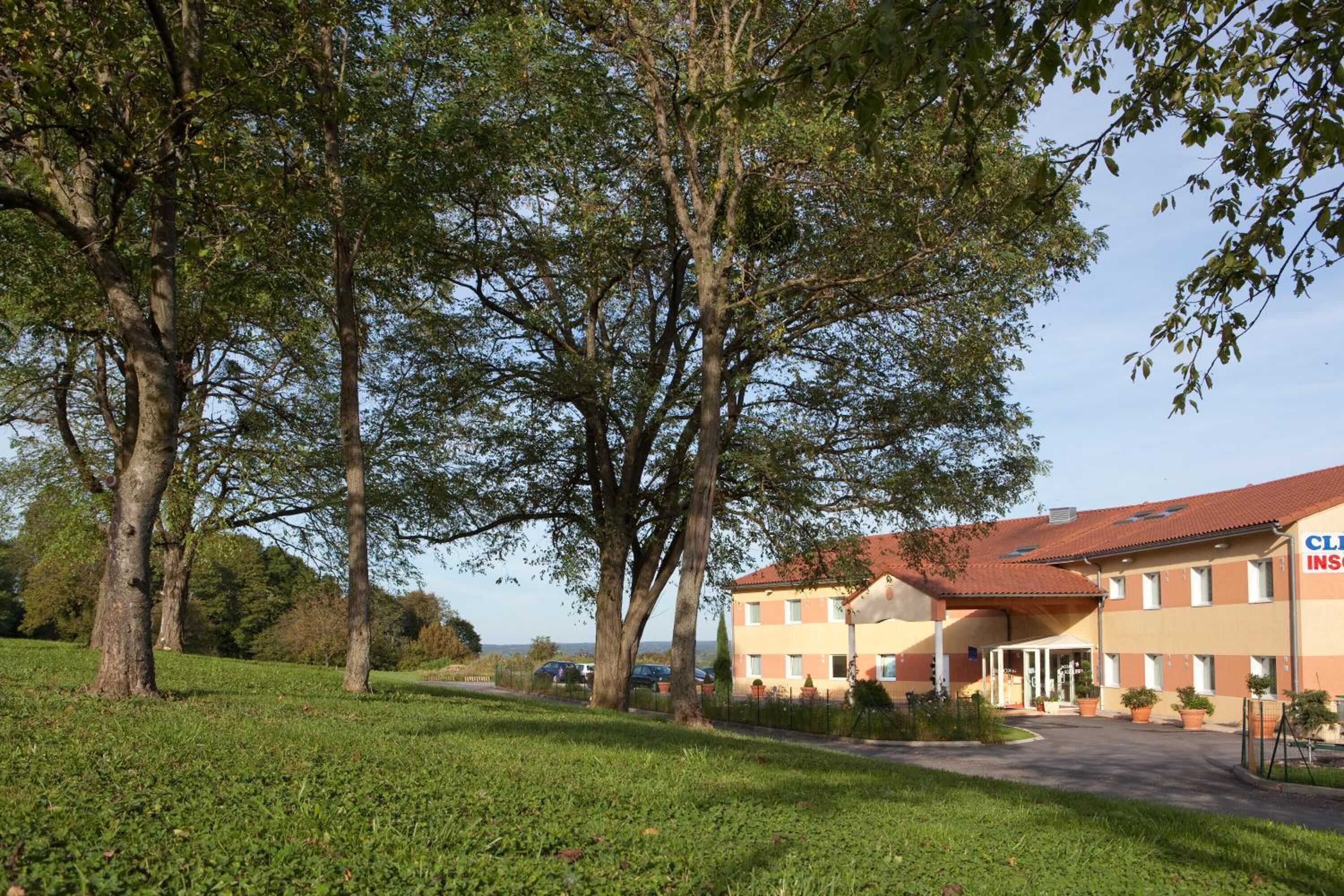 A hotel with a red-tiled roof, a covered entrance, and a parking area.
