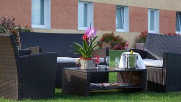 An outdoor seating area with wicker furniture, a table with a pitcher, glasses, and a book.