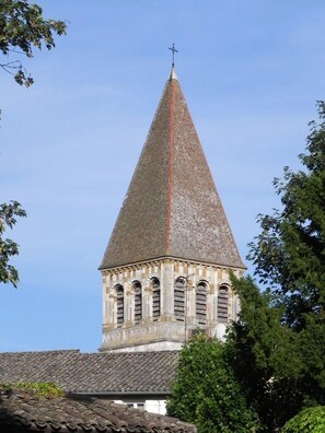 Une église dotée d’un clocher haut et effilé, surmonté d’une croix.