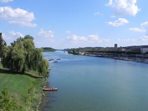 Une rivière avec un petit bateau, un pont et des bâtiments le long de la rive.