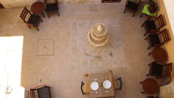 Un patio al aire libre con una mesa central preparada para dos personas, rodeada de sillas de madera.