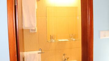 A bathroom with a wooden door, a sink, a mirror, and a towel rack.