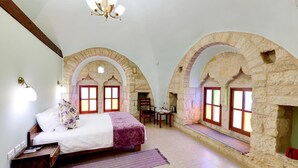 A bedroom with a bed, a chair, and a table with a lamp.