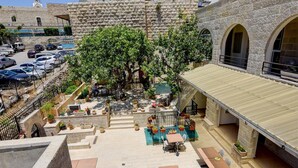 A courtyard with outdoor seating, stone walls, and a parking area.