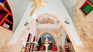 A hotel lobby with stone walls, a large star-shaped ceiling decoration, and a central fountain.