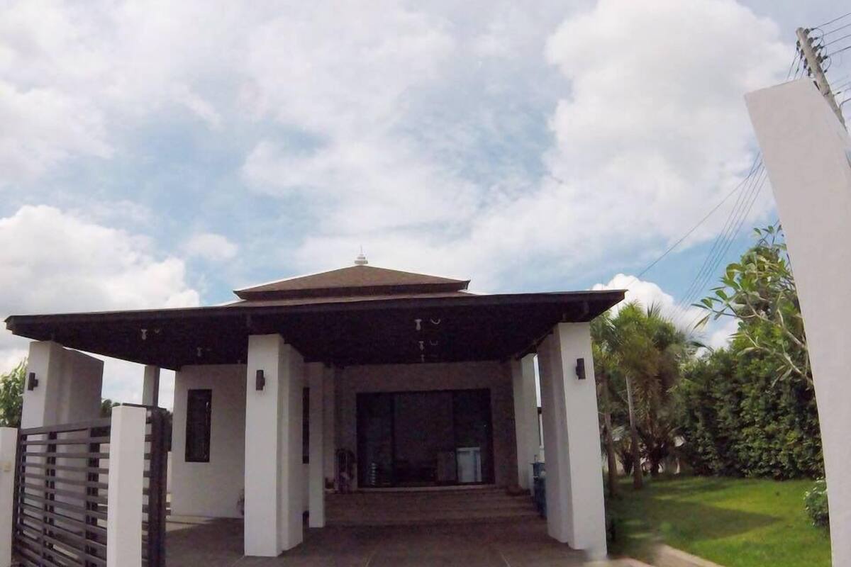 A modern building with a covered entrance, a gated driveway, and a well-maintained lawn.