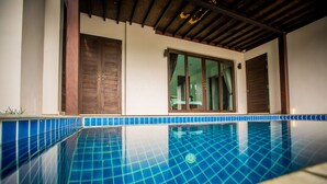A swimming pool with blue tiles, wooden doors, and a window with curtains. - Buabaan Villa (Krabi)