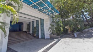 A building with a covered entrance, steps leading up to it, and surrounding greenery. - Sharrow Bay (Pattaya)