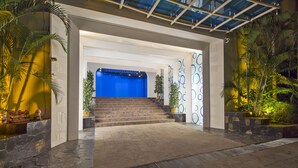 A hotel entrance with a blue reception desk, stone steps, and potted plants. - Sharrow Bay (Pattaya)