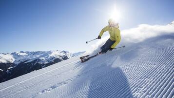A person skiing down a snow-covered slope with mountains in the background.
