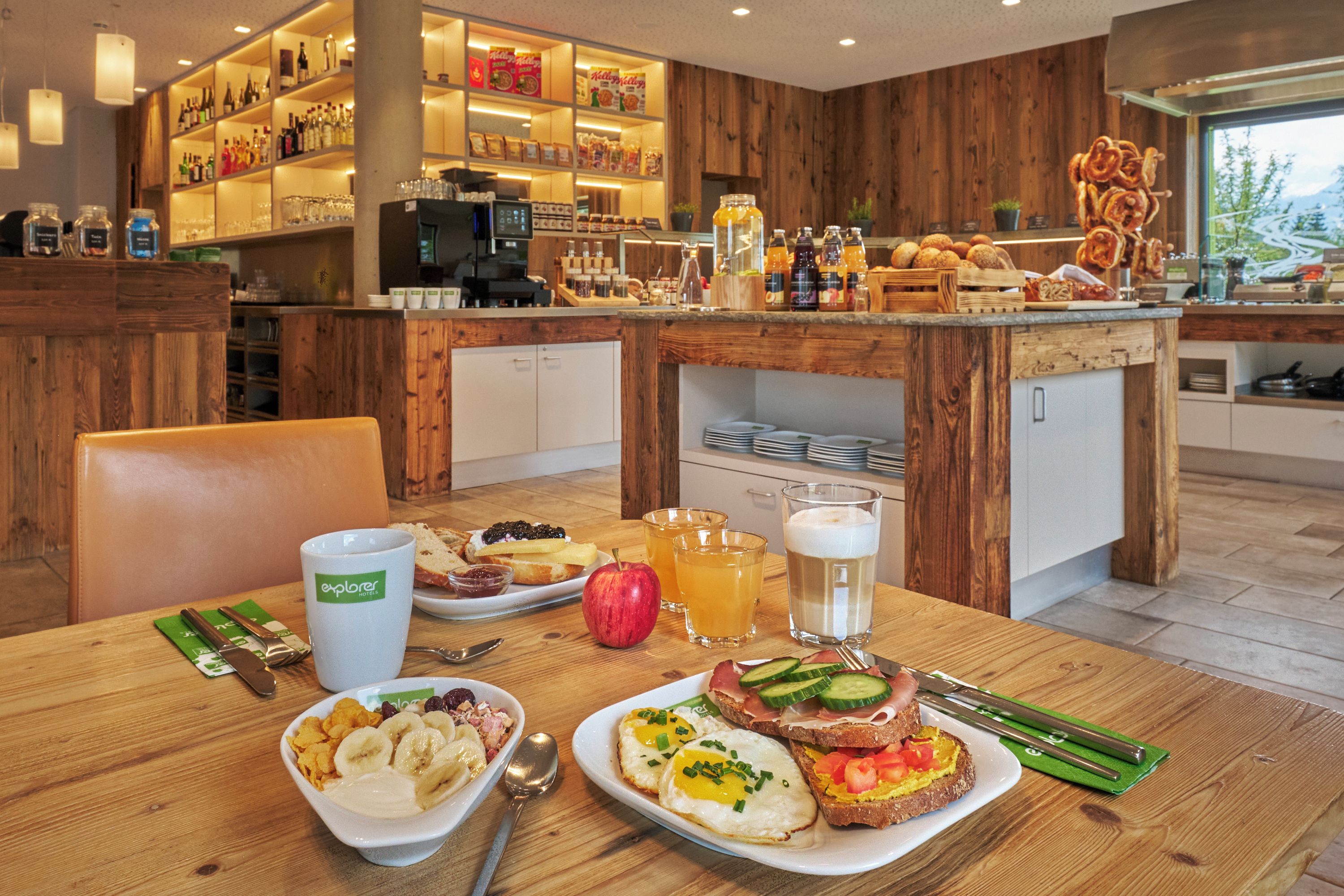 Un desayuno con diferentes opciones de comida, una cafetera y una barra con botellas y aperitivos.