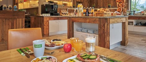 A breakfast setting with a variety of food items, a coffee machine, and a bar area with bottles and snacks.