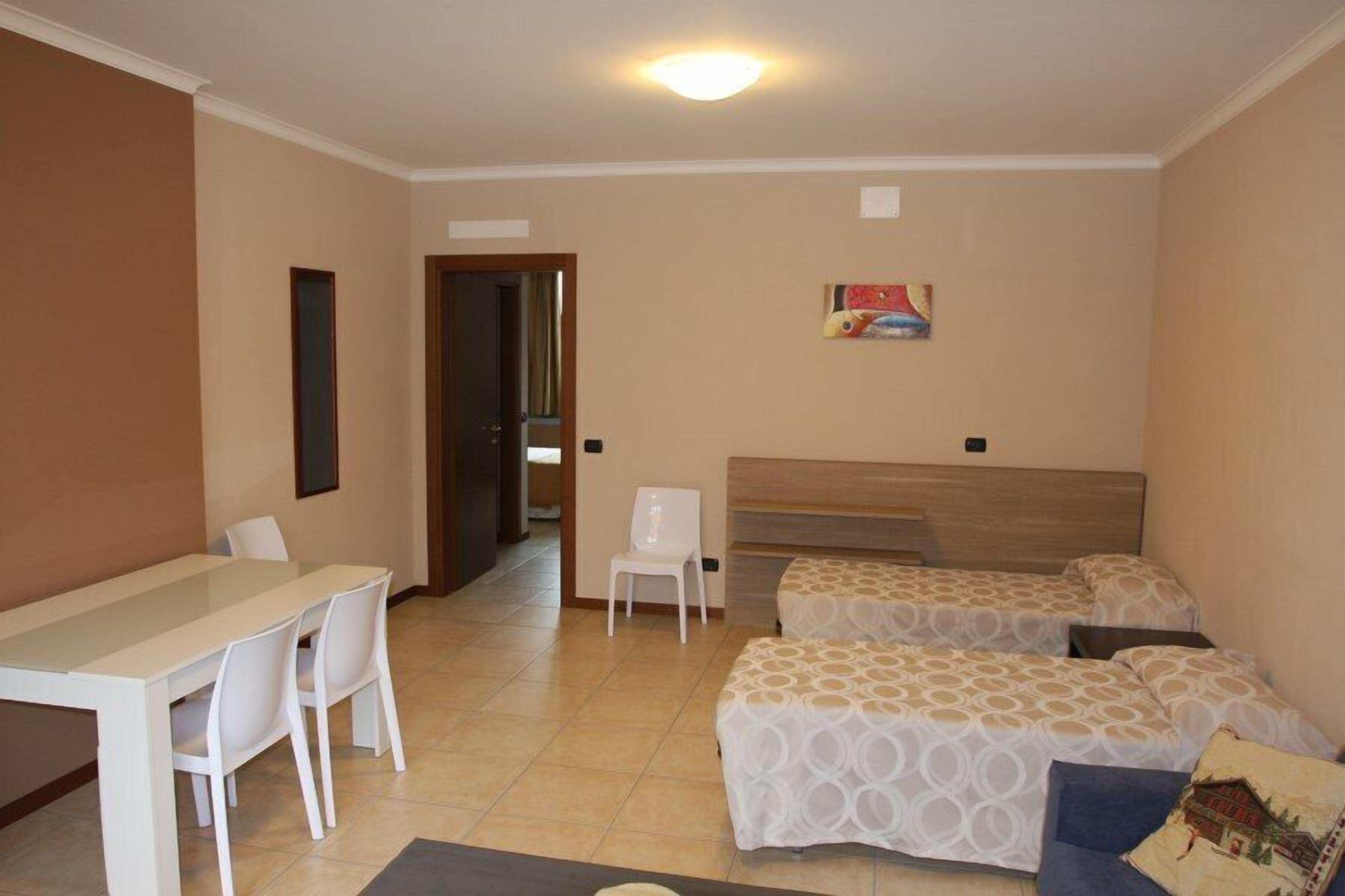 A hotel room with a bed, a desk, and chairs.
