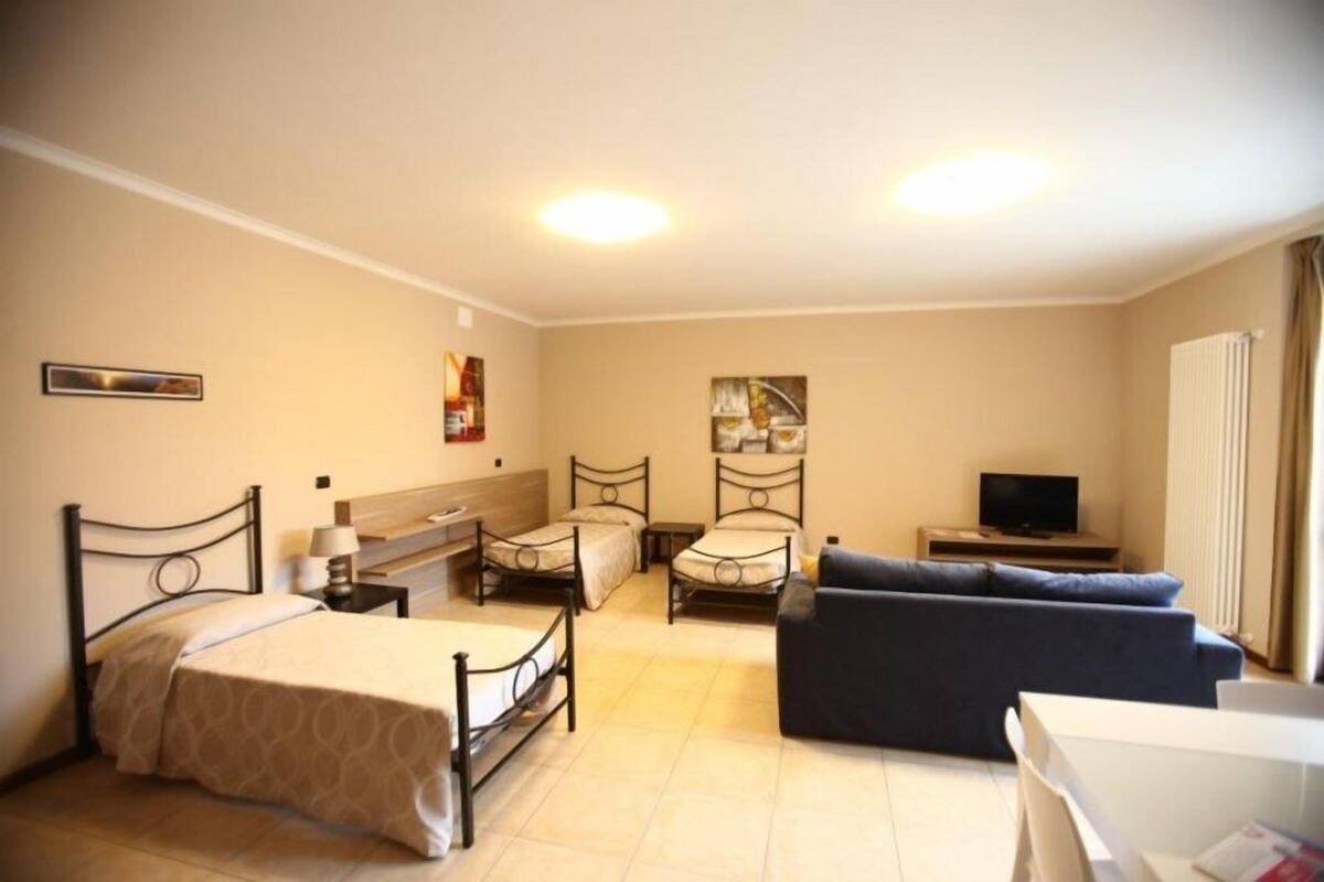 Une chambre d’hôtel avec un grand lit, deux petits lits, un canapé, une télévision et un bureau.